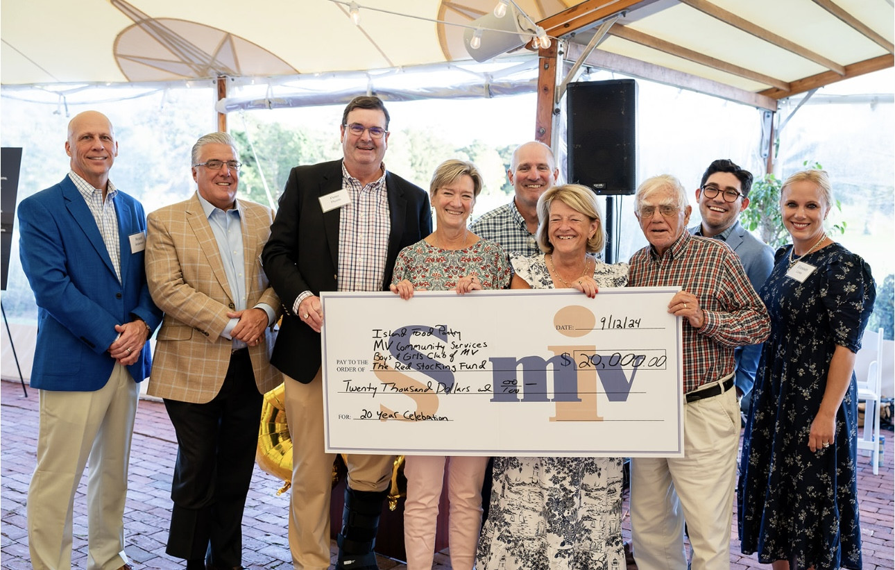 Donation ceremony with a group holding a large check for $20,000 at community event.