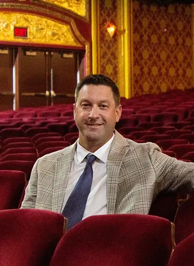 Mike McCabe, Senior VP, seated in a theatre highlighting employee benefits expertise in arts and entertainment risk solutions.