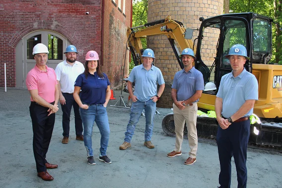 Starkweather & Shepley safety team at a construction site with hard hats and excavator.