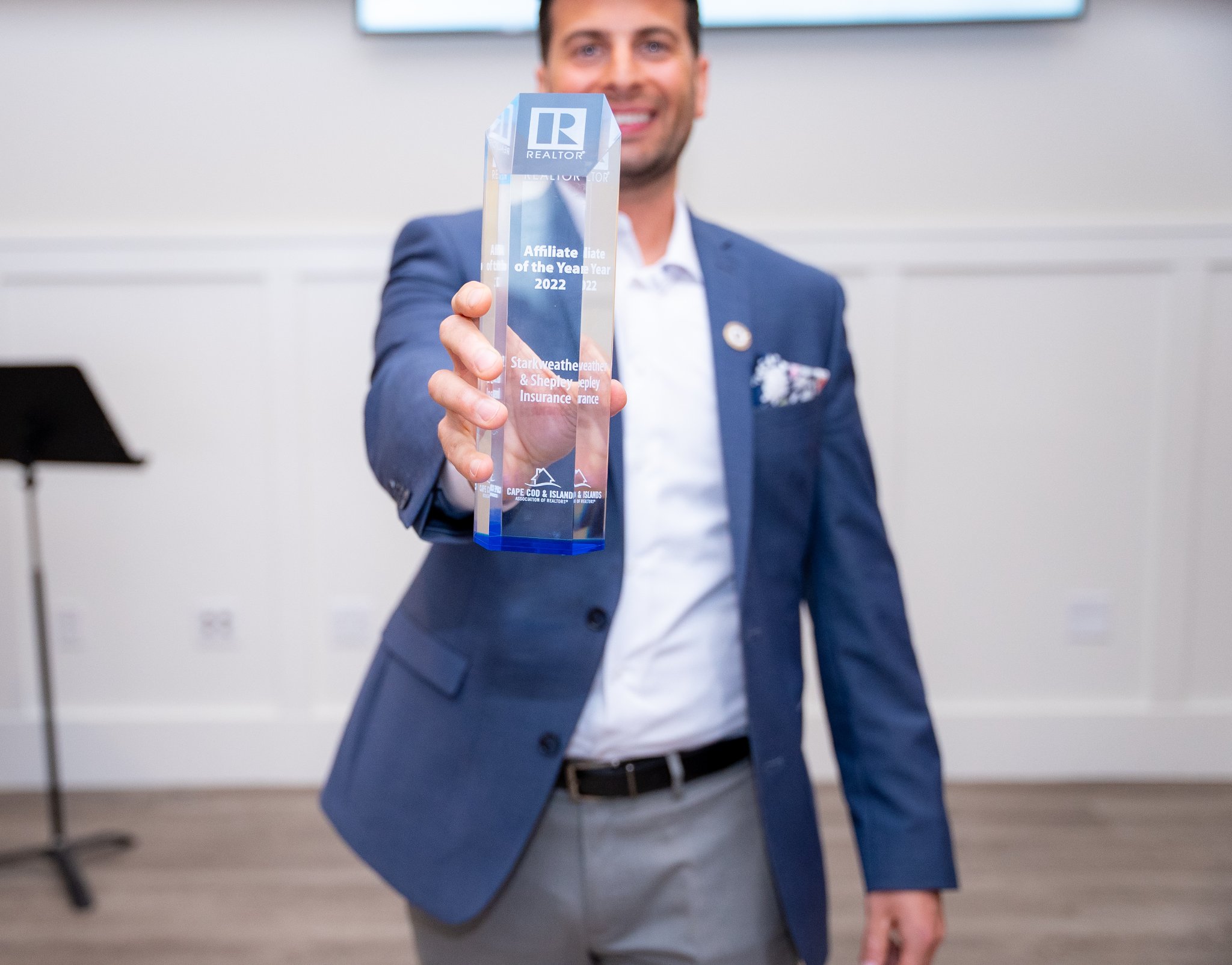 Award presentation acknowledging "Affiliate of the Year 2022" honoree in a blue suit holding a crystal trophy.