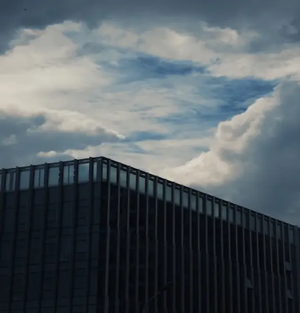 Modern office building under cloudy sky, representing employee benefits brokerage services.