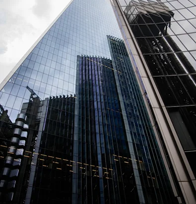 Tall glass skyscraper reflecting urban skyline, illustrating modern real estate risks and development solutions.